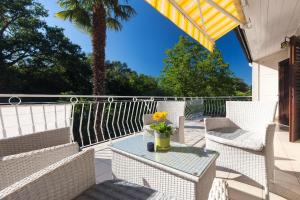 eine Terrasse mit weißen Stühlen und einem Tisch mit Blumen darauf in der Unterkunft Ferienwohnung für 3 Personen  1 Kind ca 60 m in Njivice, Kvarner Bucht Krk in Njivice