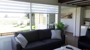 - un salon avec un canapé noir et une grande fenêtre dans l'établissement Ferienhaus am Meer mit Polderblick im Naturpark Zeeland, à Stavenisse 14 autres photos