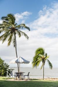 two palm trees and a table and chairs on the beach at Seaspray Yeppoon in Yeppoon