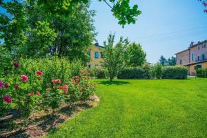 een groene tuin met bloemen en huizen op de achtergrond bij Lavanda - Studio-Apartment auf einem Bauernhof im Grünen zwischen Reggio und Modena in Scandiano