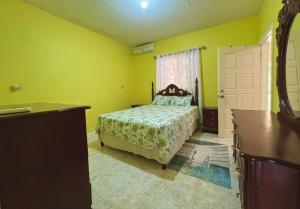 a bedroom with a bed in a yellow room at Boscobel Hillside Hideaway in St Mary
