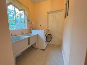 a bathroom with a washing machine and a sink at Lah's Hideaway in St Mary