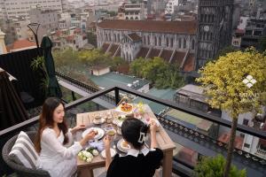 Due donne sedute a un tavolo sul balcone di GRAND HOTEL du LAC Hanoi a Hanoi