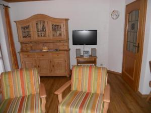 a living room with two chairs and a flat screen tv at Gemütliche Ferienwohnung mit Balkonen, direkt im Ortszentrum von Reit im Winkl in Reit im Winkl