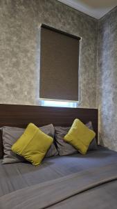- un lit avec 2 oreillers jaunes et une fenêtre dans l'établissement Casa Kota Residence, à Jakarta