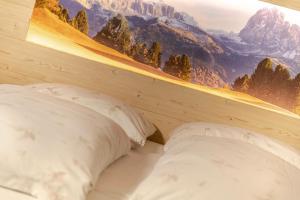 a bed with two pillows and a picture of mountains at Chalet im Grünen in den Suedtiroler Dolomiten mit 17 Betten in Selva di Val Gardena