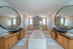 a bathroom with two sinks and a large mirror at Villa Namaskar - Iconic 5BR Cliff Top Villa - 180° Ocean View in Jimbaran