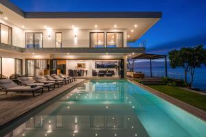 Villa Namaskar - Iconic 5BR Cliff Top Villa - 180° Ocean View في جيمباران: منزل به حمام سباحة في الليل