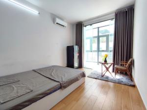 Schlafzimmer mit einem Bett, einem Tisch und einem Fenster in der Unterkunft Yên House 09 in Ho-Chi-Minh-Stadt