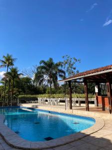a large swimming pool with a pavilion and palm trees at Pousada Vale das Flores in Penedo