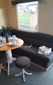 a couch with a table and a table and chairs at Cosy holiday home stay in Great Clacton