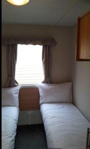 two beds in a small room with a window at Cosy holiday home stay in Great Clacton