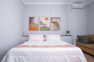 a white bedroom with a bed and a couch at Brownies House in Bandung