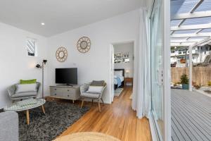 a living room with a television and a room with a bedroom at Escape to Kohi Cottage - Your Beachside Haven in Auckland