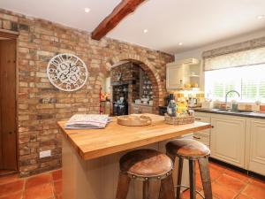 una cocina con una pared de ladrillo y una barra con taburetes en Coronation Cottage, en Wisbech