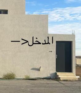 un edificio con escritura arábiga en el costado. en نزل الزلفي لشقق المخدومة, en Az Zulfi
