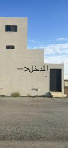 un edificio con escritura arábiga en el costado. en نزل الزلفي لشقق المخدومة, en Az Zulfi