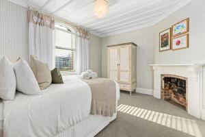 a bedroom with a white bed and a fireplace at 3BR Boutique Villa Walk to SPARK Arena w Parking in Auckland