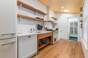 Il comprend une cuisine avec des appareils électroménagers blancs et du parquet. dans l'établissement 3BR Boutique Villa Walk to SPARK Arena w Parking, à Auckland