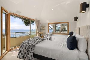 Un dormitorio con una cama y vista al mar. en Takapuna Beachfront w Stunning Views, en Auckland