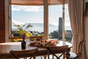 奧克蘭的住宿－Takapuna Beachfront w Stunning Views，窗口顶上一张桌子,上面有盘子的食物
