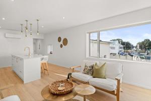 a living room with a white couch and a table at Luxury Apart, Seaviews & Balcony, Full Kitchen & Heat Pump in Auckland
