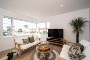 a living room with white furniture and a flat screen tv at Luxury Apart, Seaviews & Balcony, Full Kitchen & Heat Pump in Auckland