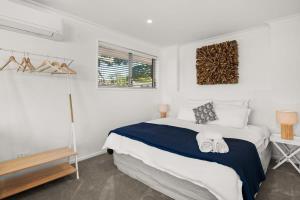 Stay Coastal - Tauranga في تاورانجا: غرفة نوم بيضاء بها سرير ونافذة