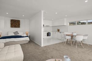 Stay Coastal - Tauranga في تاورانجا: غرفة نوم بيضاء مع سرير وطاولة