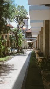 a walkway between buildings with benches and trees at New Puri Asih Hotel in Kuta