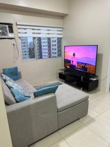 a living room with a couch and a flat screen tv at Elegant 2 Bedroom Unit @Avida#27 in Iloilo City
