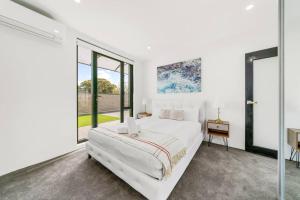 a white bedroom with a large bed and large windows at King’s Deluxe in Newtown in Sydney