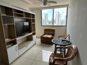 ein Wohnzimmer mit einem TV, einem Tisch und einem Stuhl in der Unterkunft Hermoso Apto Completo Amoblado in Panama-Stadt