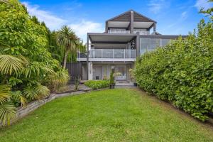una casa grande con césped delante en Ocean View Spacious 5BR Retreat for Families en Auckland