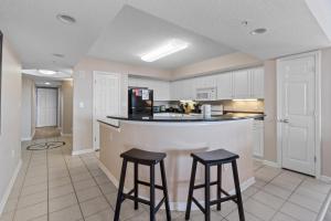 a kitchen with two bar stools and a counter top at Yacht Club Villas #1-701 condo in Myrtle Beach