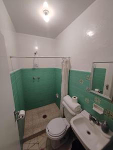 a green and white bathroom with a toilet and sink at Departamento amplio con hermosa vista in Puebla