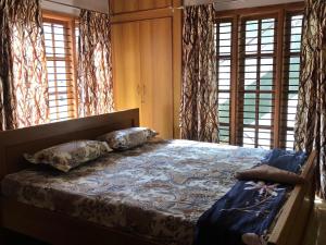 a bedroom with a bed with pillows and windows at Mahagiri Nest in Mysore