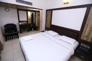 a bedroom with a large white bed and a chair at WESTLAND HOTEL- ERODE in Erode
