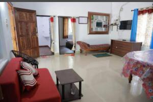 Noble Homestay في مونار: غرفة معيشة مع أريكة حمراء وطاولة