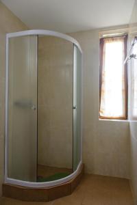 a glass shower in a bathroom with a window at Pensiunea Aries in Arieşeni