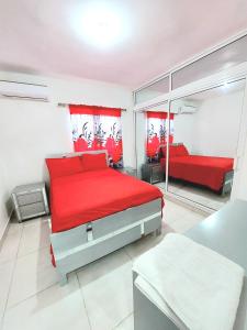 - une chambre avec un lit rouge et un miroir dans l'établissement ¡Tu refugio tropical en La Romana!, à La Romana