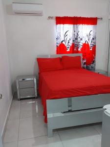 - une chambre avec un lit rouge et un rideau rouge dans l'établissement ¡Tu refugio tropical en La Romana!, à La Romana