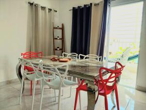 une salle à manger avec une table en verre et des chaises rouges dans l'établissement ¡Tu refugio tropical en La Romana!, à La Romana