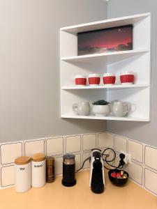 a kitchen counter with cups and appliances on a shelf at Rockingham Palace in Rockingham