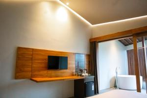 1 dormitorio con TV en la pared en Agua Hotel, en Kubupenlokan