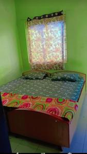 a bed in a green room with a window at On Hill Rooms in Yercaud