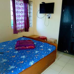 Schlafzimmer mit einem Bett mit blauer Decke und einem TV in der Unterkunft On Hill Rooms in Yercaud