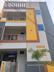 a building with a yellow door and a balcony at RRRHomestay in Tirupati