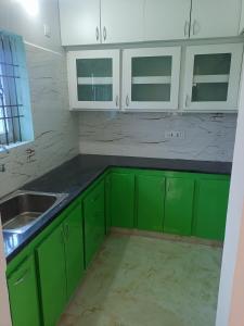 a kitchen with green cabinets and a sink at RRRHomestay in Tirupati