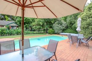 um pátio com uma mesa, um guarda-sol e uma piscina em Silver Birches Holiday Village - Unit 9 em Bright